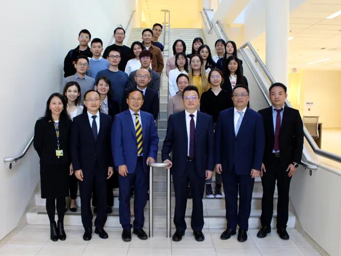 A large group of people dressed in business wear standing on stairs for a photo