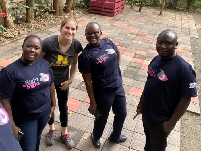 Four people wearing dark t-shirts and posing for a photo outside