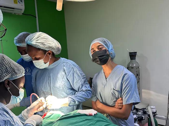 Medical students wearing scrubs and surgical masks working on the operation table