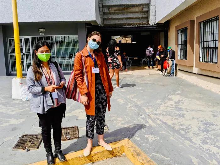 Two women wearing facemasks standing outside a building 
