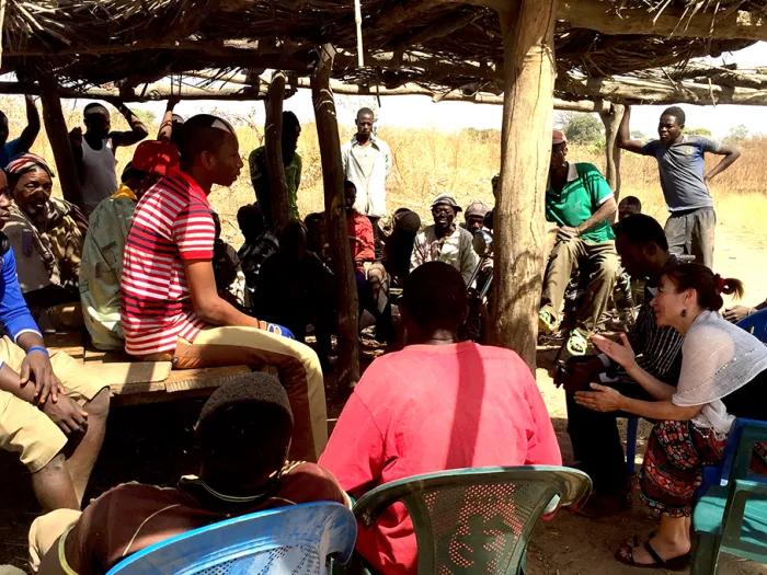 Group of people sitting under a thatched roof 