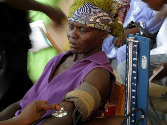 Woman in a purple tunic and purple and yellow patterned headscarf getting her blood pressure taken