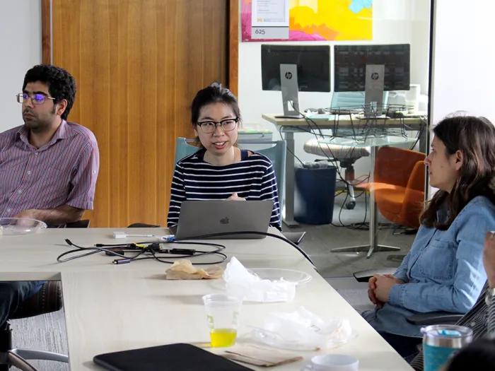 Four people sitting around tables arranged in a 'U' shape 