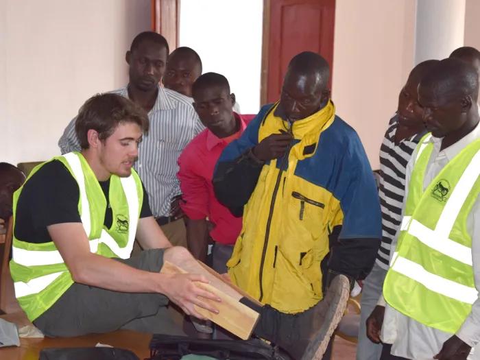 Man with neon yellow safety vest explaining something to a group of people standing around him