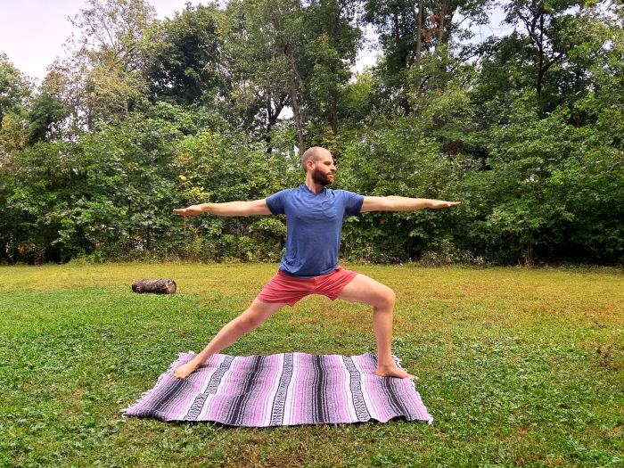 man practicing yoga outside over blanket