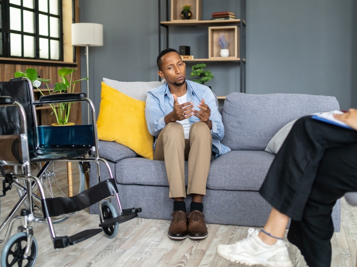 person sitting on couch wheelchair talking to someone 