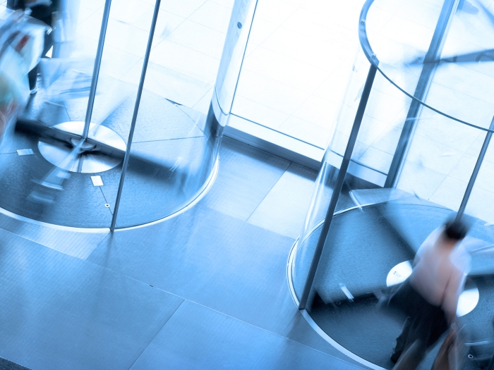 blurred front door exit with people walking through in blue see through doors