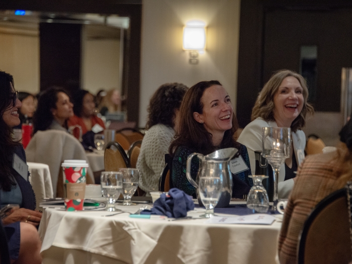 A room with several women laughing around tables.