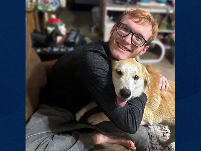 young adult male hugging blonde haired dog