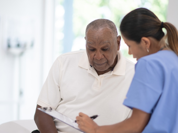 patient looking at paper with provider in scrubs blue in clinic 