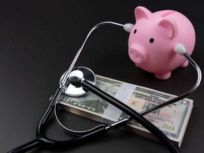 pink little pig bank listening to money with a stethoscope on a black table