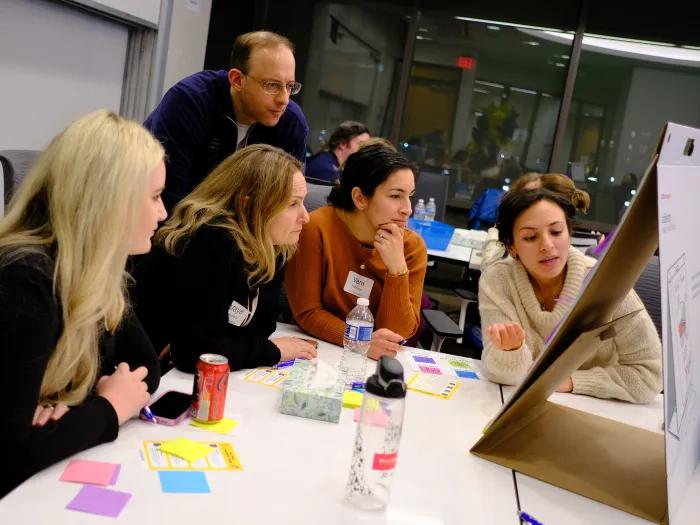 Group of people looking at post-it board.