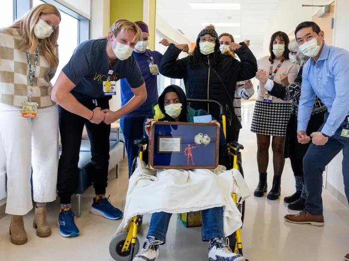 clinical team in hallway with masks on and making strong poses around kid