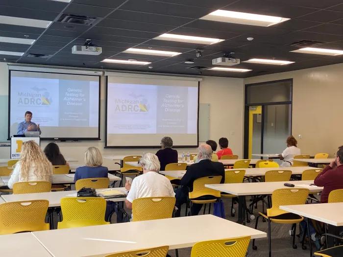 a faculty member presenting to a group of people at the Detroit Center 