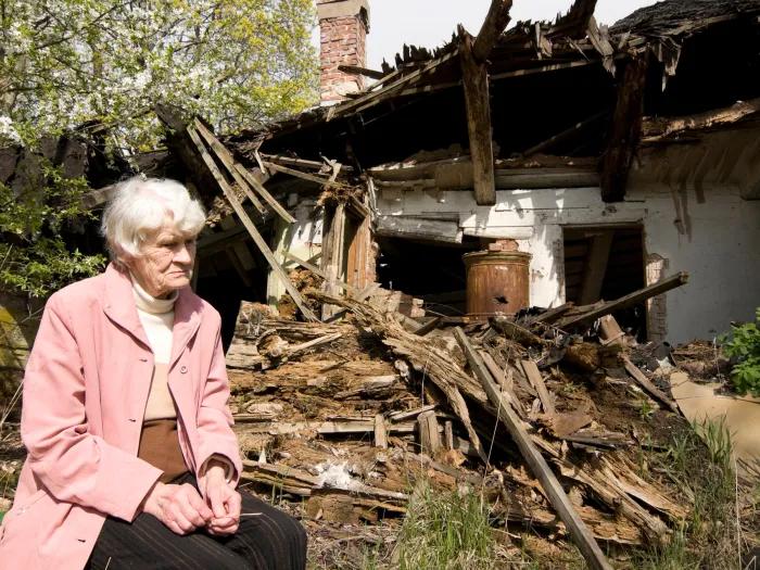 woman sitting outside home destoryed