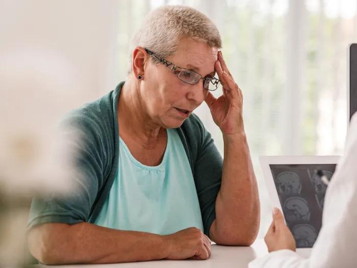woman touching head talking to front desk person
