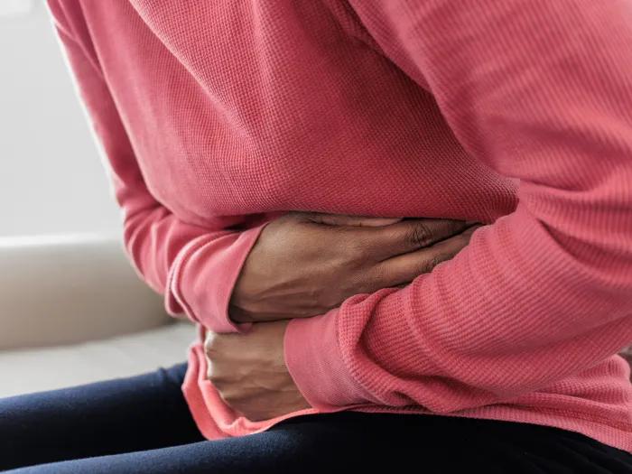 bent over holding stomach pink shirt sitting