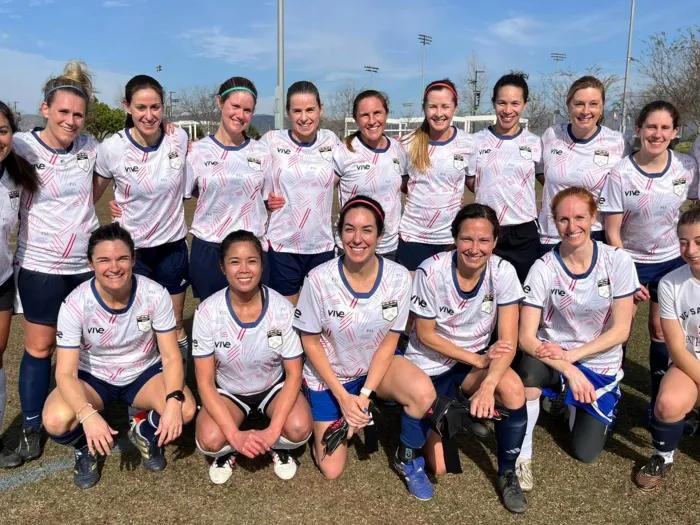women's soccer team in white jerseys posing for picture