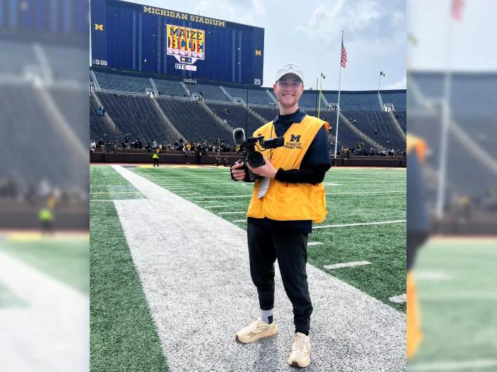kid on field smiling in UM gear on UM football field