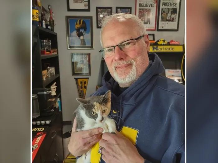 man holding cat in michigan sweater