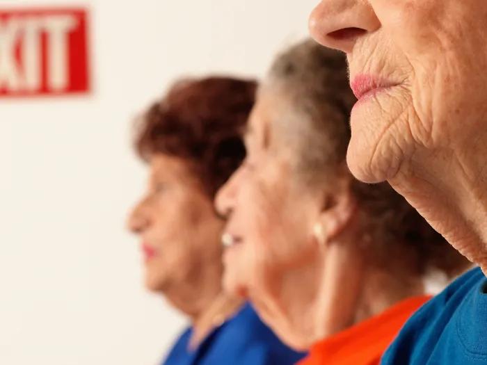older women close up and blurred out by faces with an exit sign far away in red background and white writing