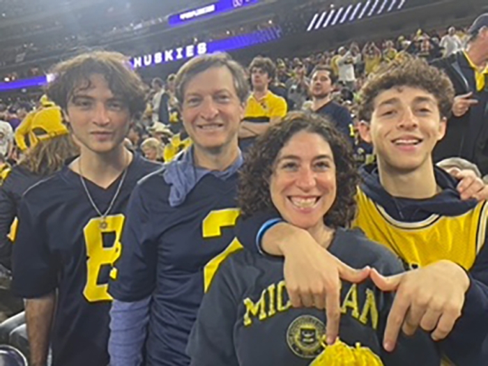 Smiling photo of the Saiontz family wearing U-M gear at a football game.