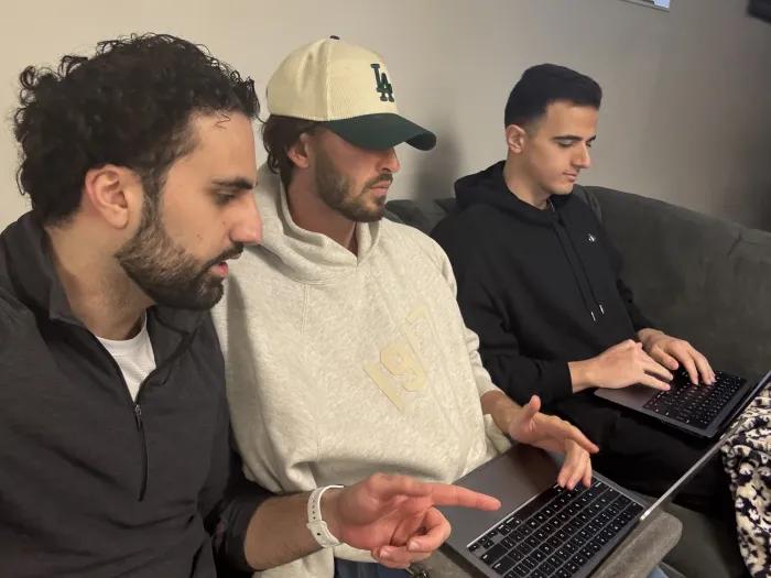Three medical students sit on a couch working on laptops