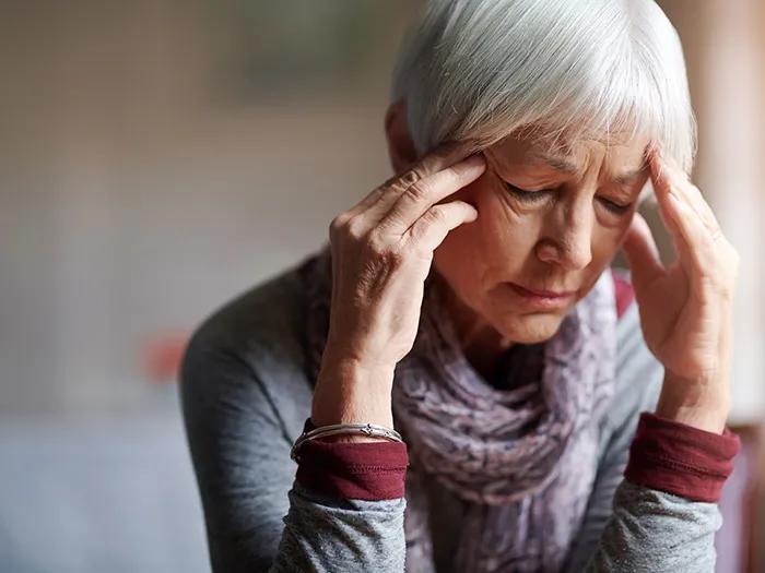 giant cell arteritis (GCA) elderly woman holding temples closing her eyes