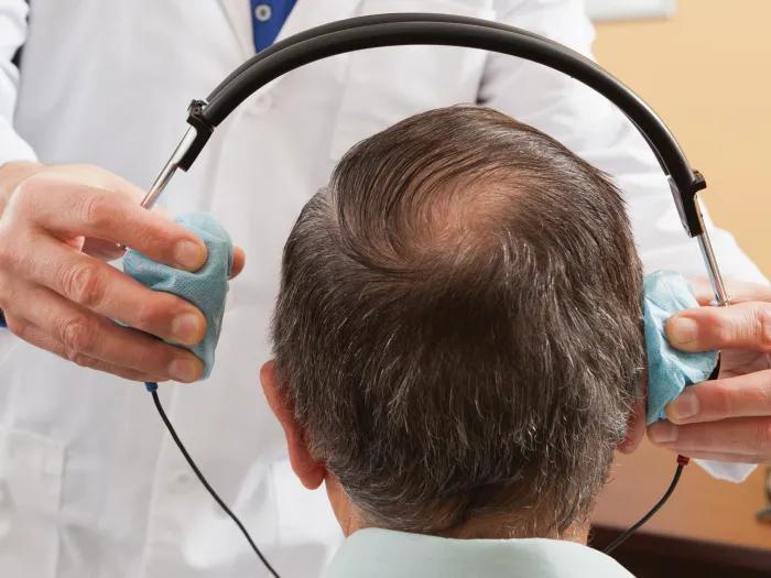 up close head with headphones going on patients head seeing from back of head