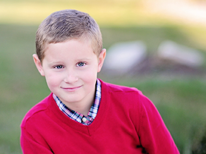 Smiling portrait of Jack Fineske. He has short brown hair and is wearing a red sweater.