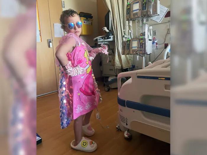 little girl posing sassy in pink dress hospital room