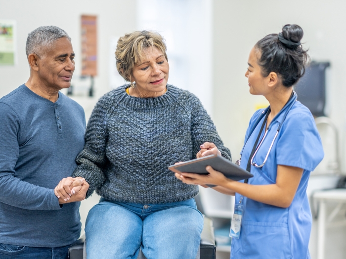 older woman with older man with nurse at office