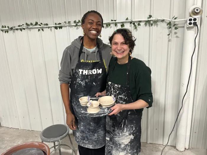 Two women holding freshly thrown pottery