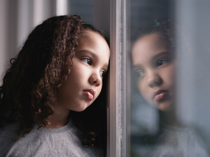 little girl looking sad out the window