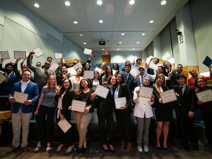 Lecture hall full of nicely dressed students showing their certificates
