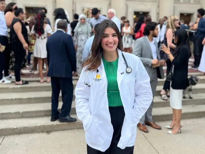 Medical student Yara wears a white coat and stethoscope outside the White Coat Ceremony