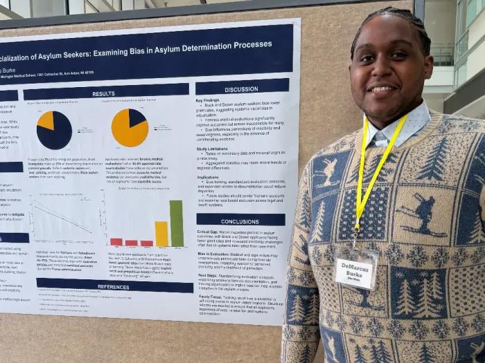 A man stands next to a research poster