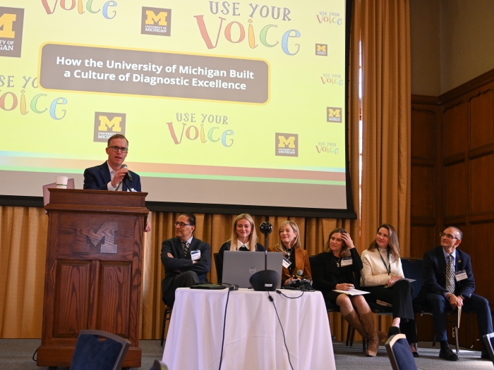 A panel sits on stage and speak