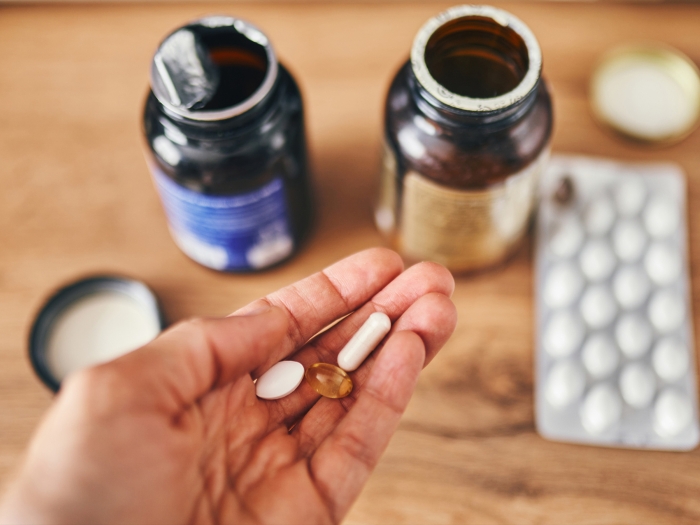pills in hand with pill bottles open