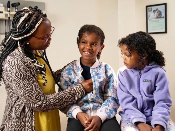 female pediatric physician checks heart rate of young boy