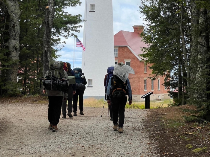 Students backpack towards a lighthouse