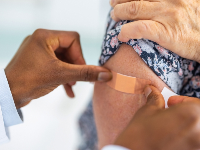 hand putting band aid on persons arm