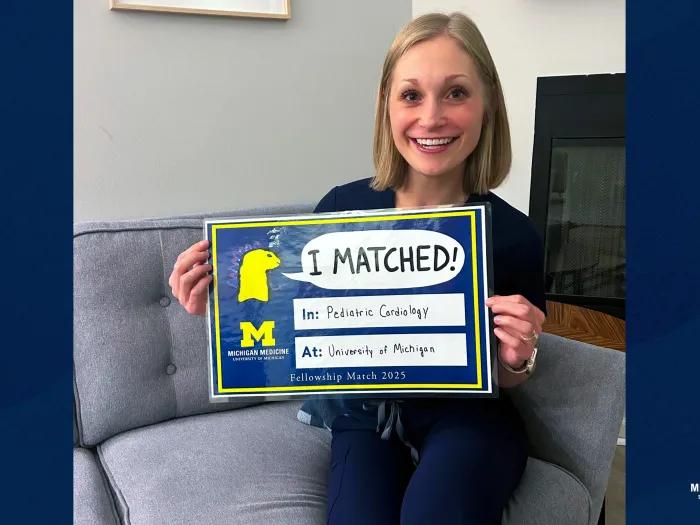 girl with short blonde hair holding a sign that says she matched to michigan residency 