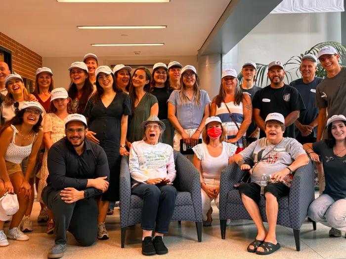 group of people smiling and posing with white hat