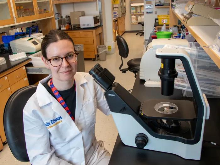 Nicole Edwards in the lab with a microscope