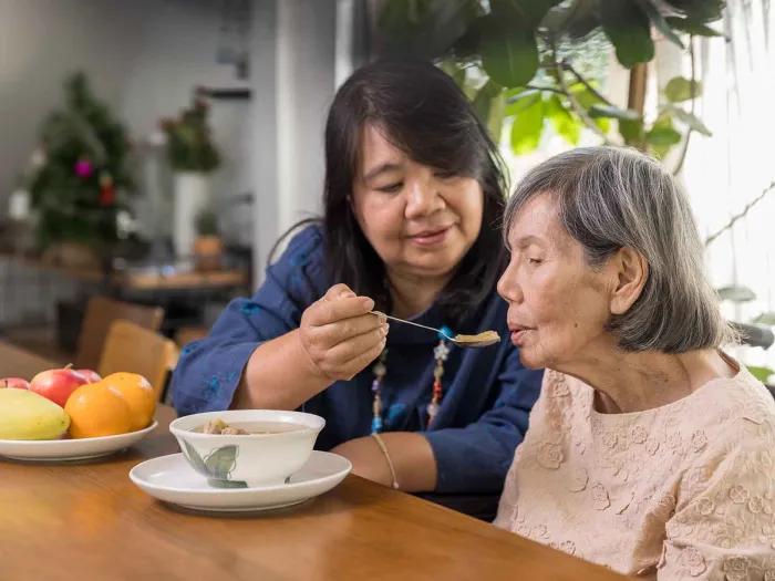 Family caregiver feeding older woman