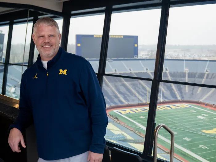 Man in a blue pullover against the background of Michigan Stadium