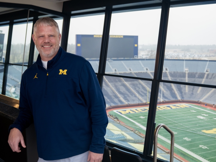 Man in a blue pullover against the background of Michigan Stadium