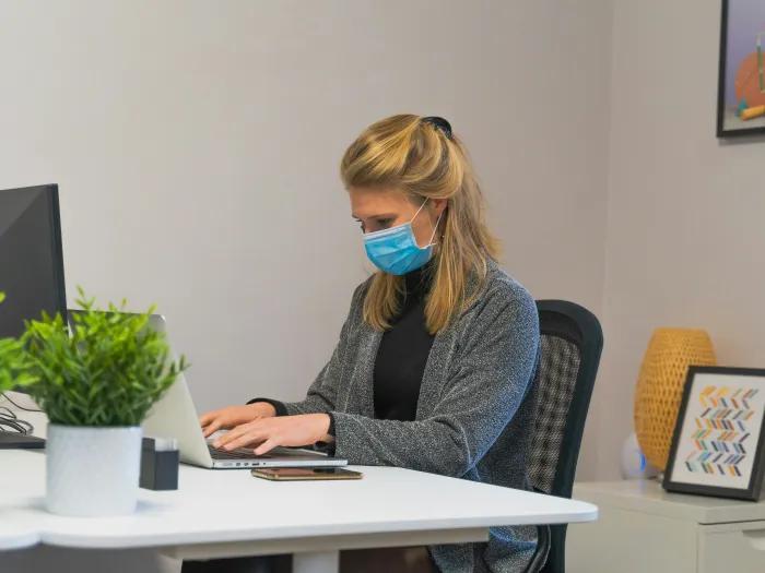 a clinician sitting at her desk and typing on a laptop keyboard