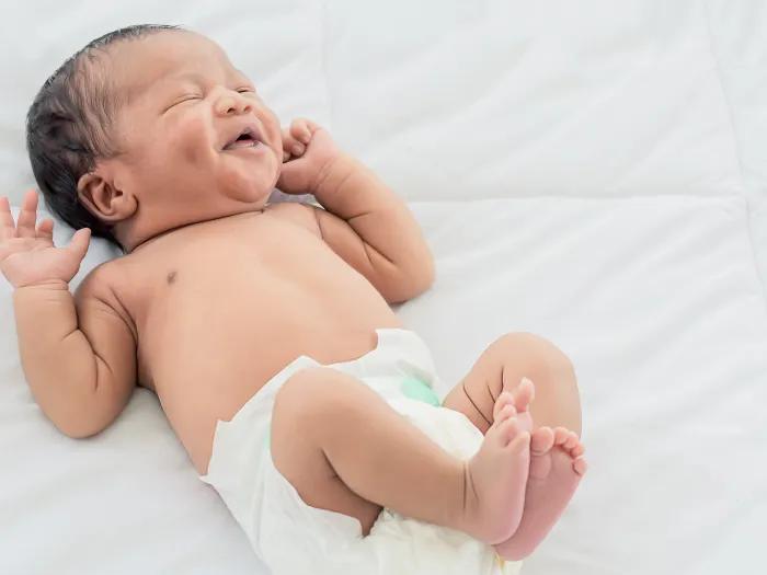 baby laughing on bed in diaper